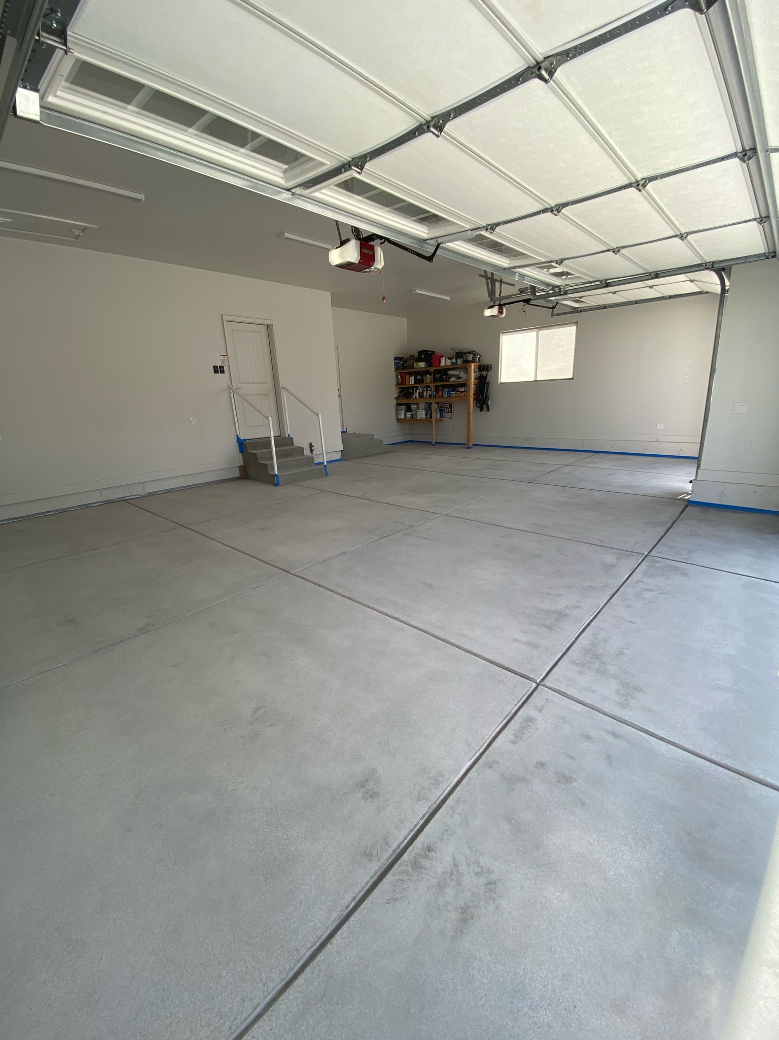 Bare concrete garage floor with blue tape edge prep before coating - Sparks Coatings
